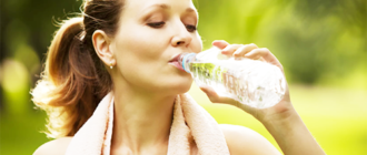 спортсменка пьет воду из пластиковой бутылки